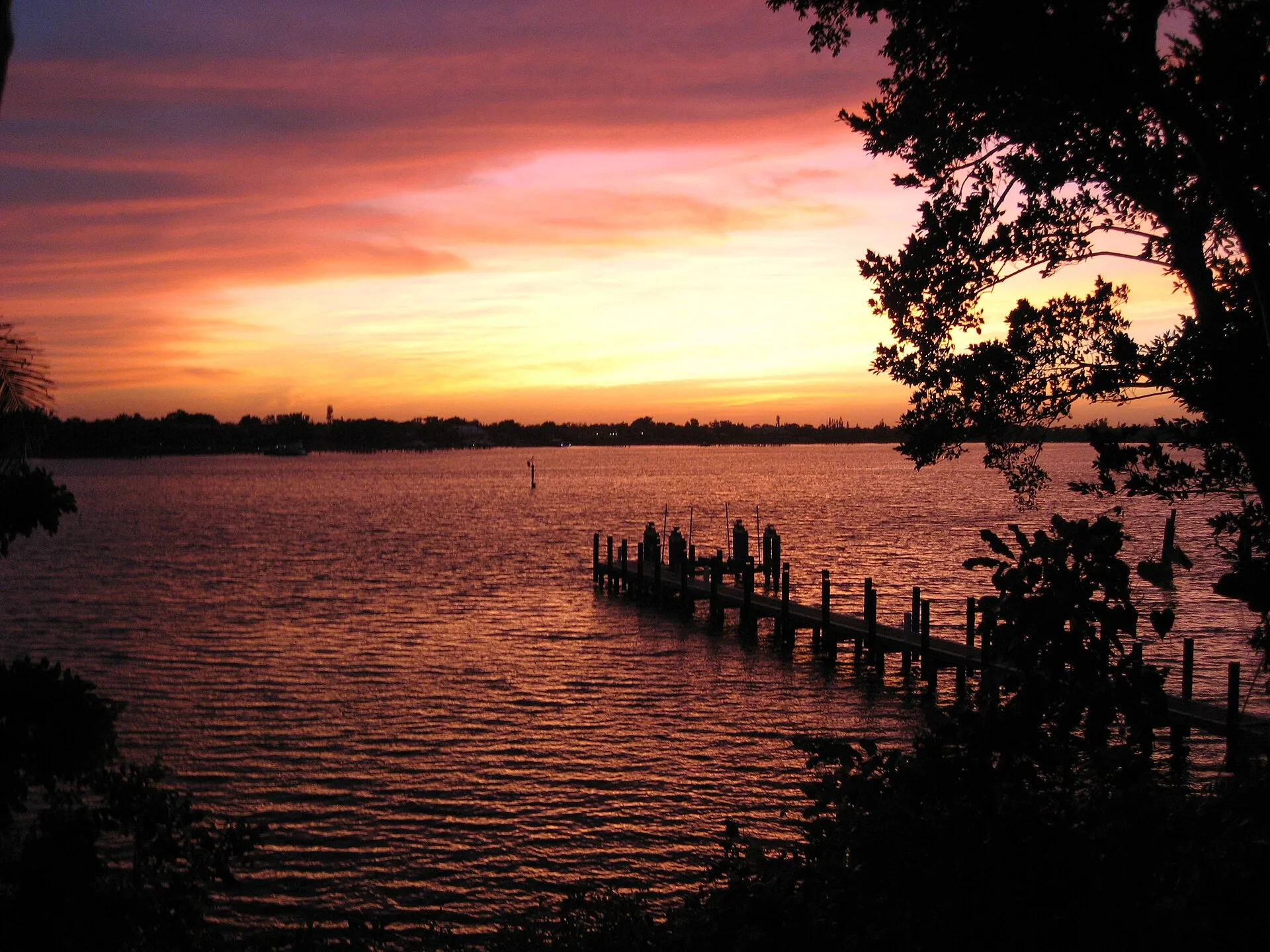 St. Lucie River at dusk with a silhouetted dock and palm fronds